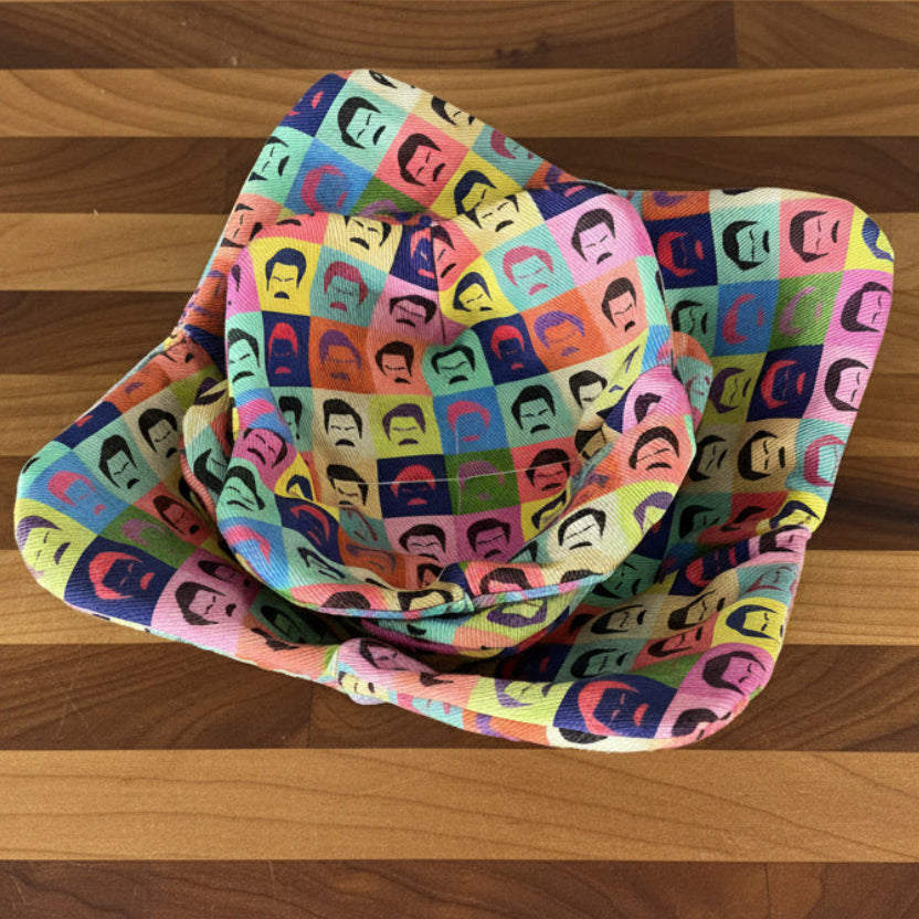 Colorful fabric with a pattern of mustachioed faces on a gray surface