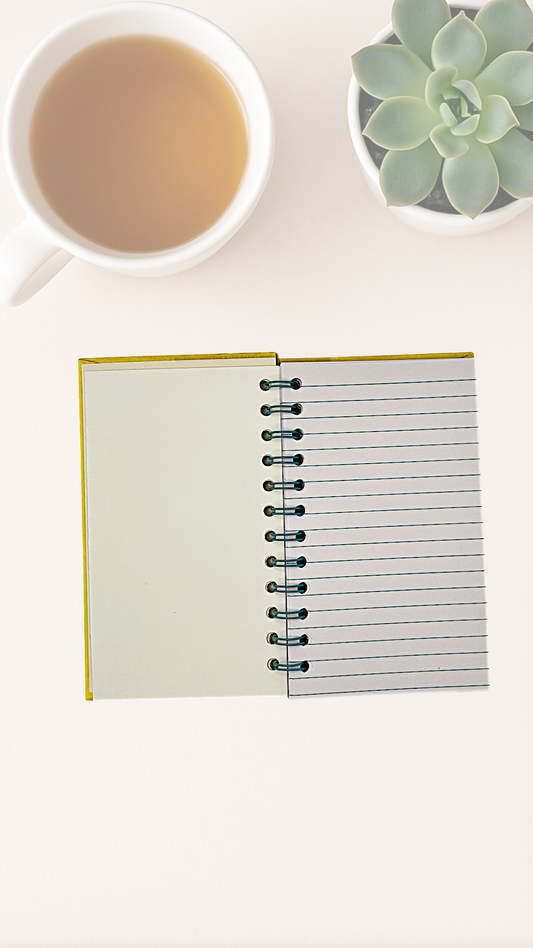 Open notebook with a cup of tea and succulent plant on a white surface