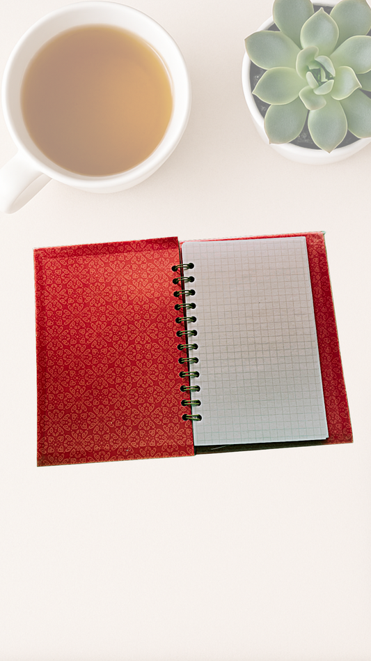Inside cover - Red notebook with a white grid page, next to a cup of tea and a succulent plant on a light surface.