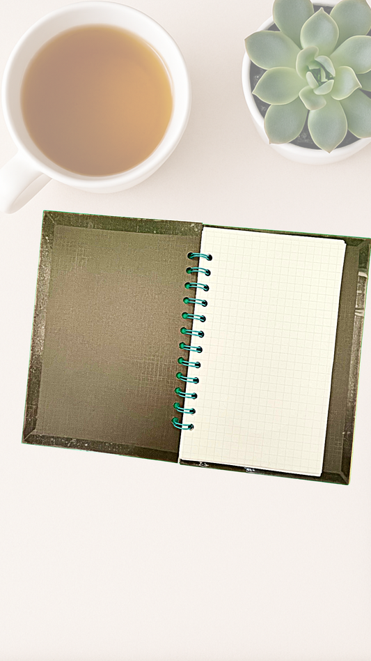 Notebook with a cup of tea and a succulent plant on a white surface