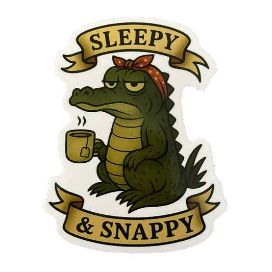 Sticker of a crocodile holding a mug with 'Sleepy & Snappy' text on a white background
