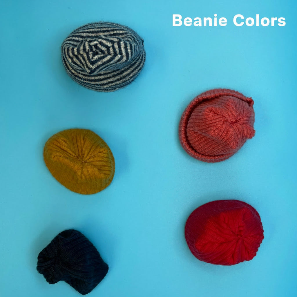 Five knitted skullcaps in different colors and patterns are arranged on a solid light blue background. The colors include black and white stripes, mustard yellow, red, and dark navy blue.