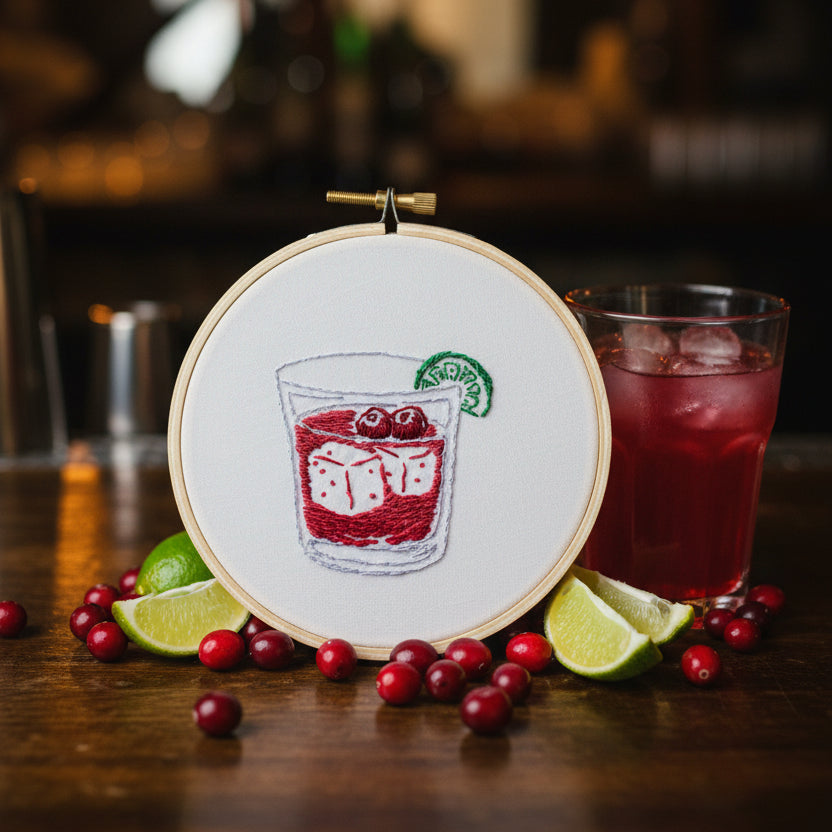 Embroidery hoop with a Cape Cod cranberry drink with a lime and two ice cubes
