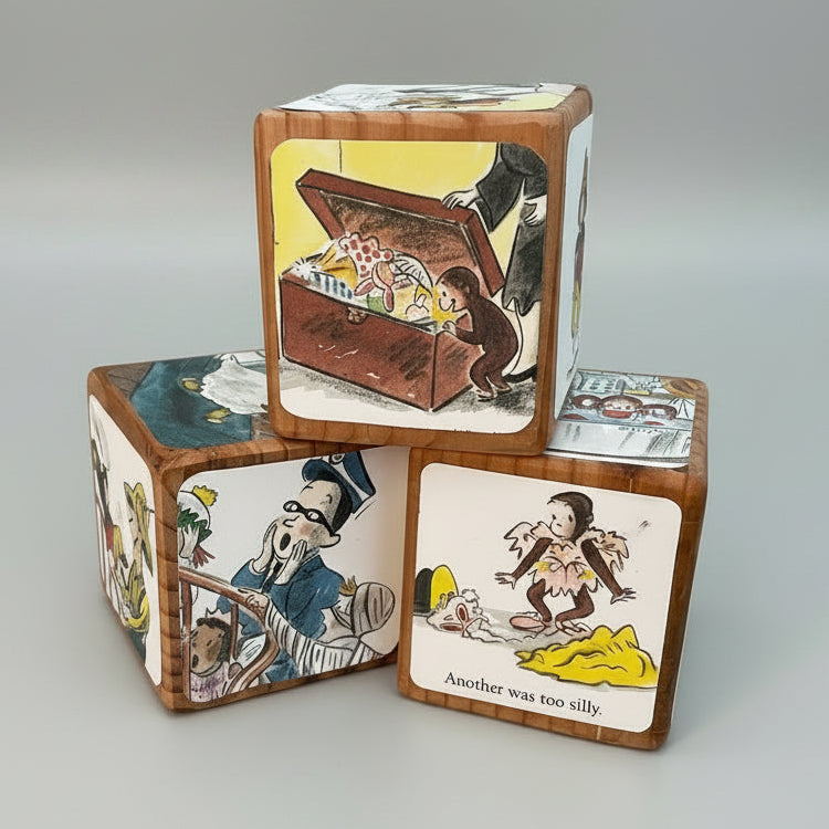 Wooden blocks with Curious George illustrated scenes on a desk