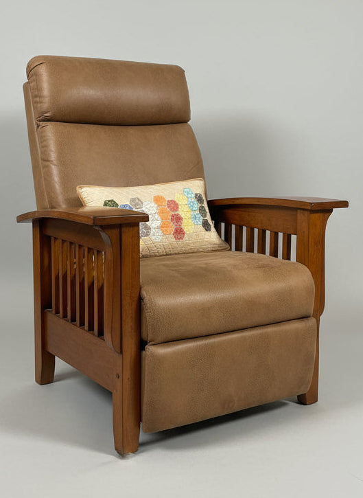Brown armchair with a colorful pillow in a room with a window and light fixture.