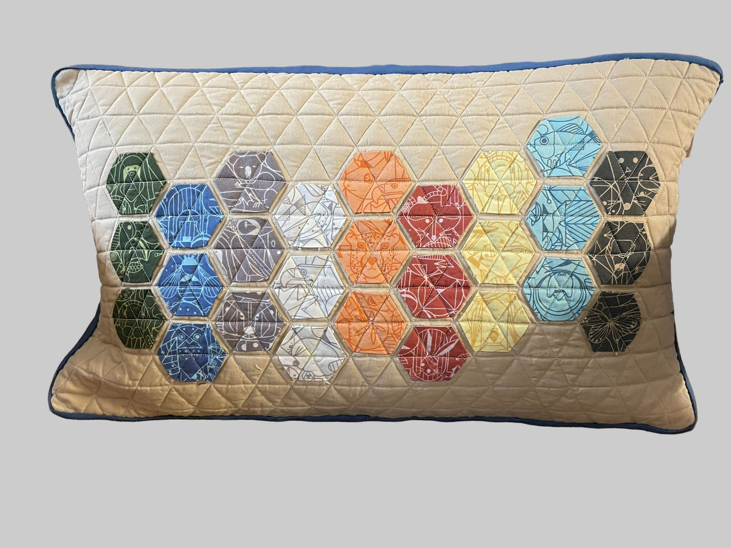 Quilted Charley Harper pillow with hexagonal pattern on a brown chair