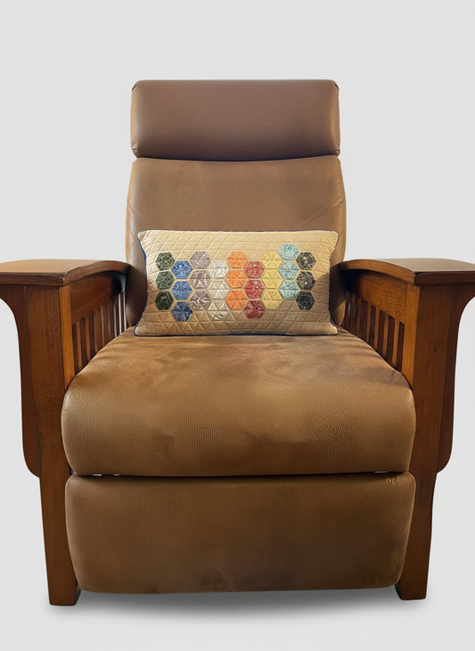 Brown armchair with a colorful Charley Harper Endpapers fabric hexagonal patterned pillow in a living room setting.