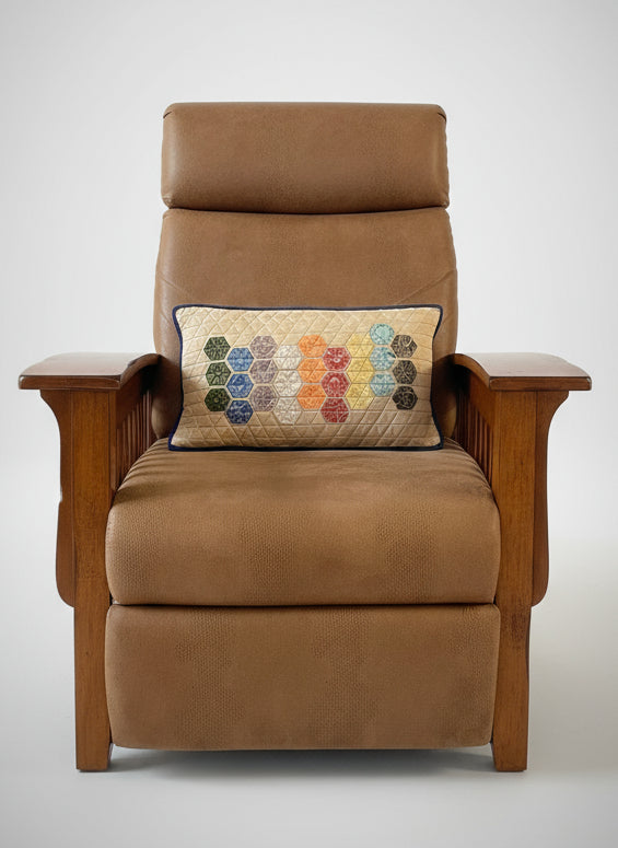 Brown armchair with a colorful hexagonal patterned pillow in a room with a sliding glass door.