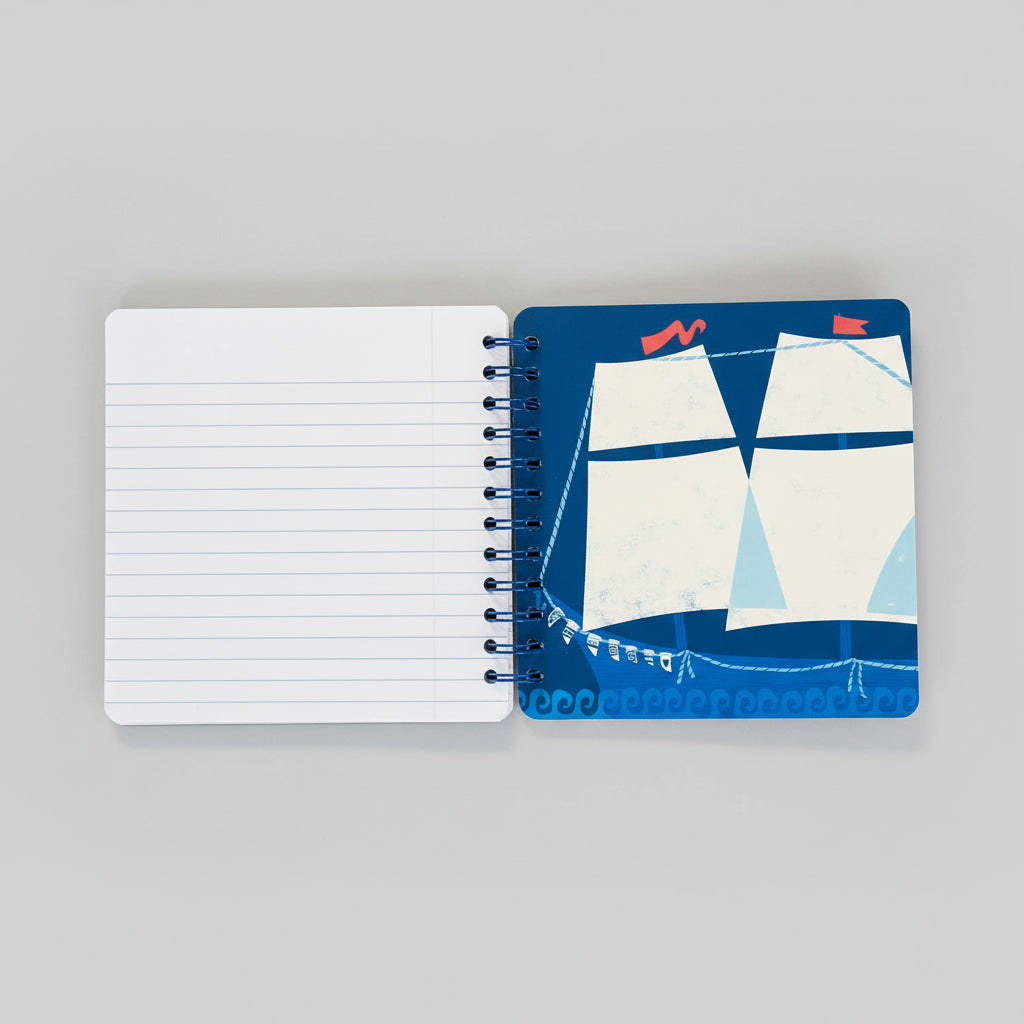 Notebook with a sailboat design on the cover, open to reveal lined pages, on a brown background.