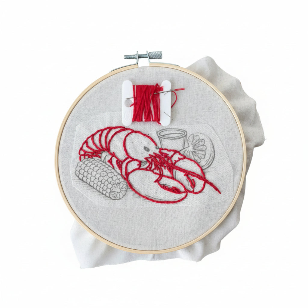 Embroidery hoop with red lobster design on a white fabric background