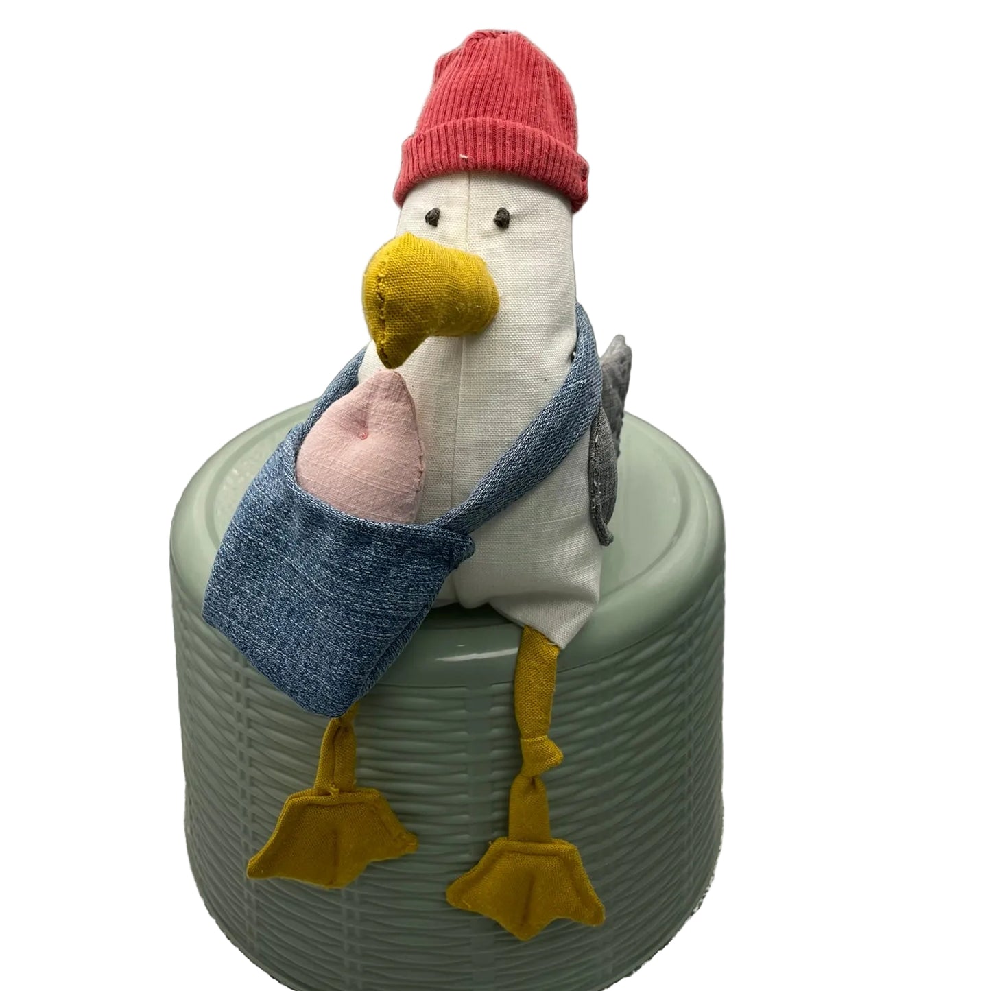 Stuffed toy seagull wearing a red hat with a denim bag and pink fish