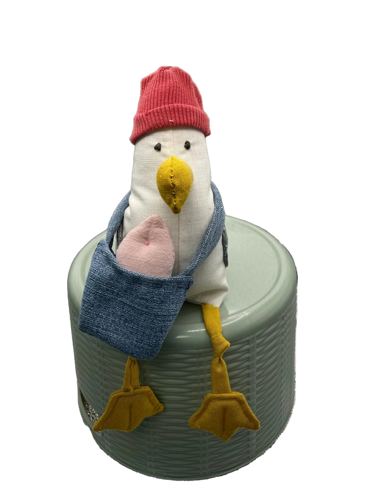 Stuffed toy seagull wearing a red hat and blue bag with a pink fish