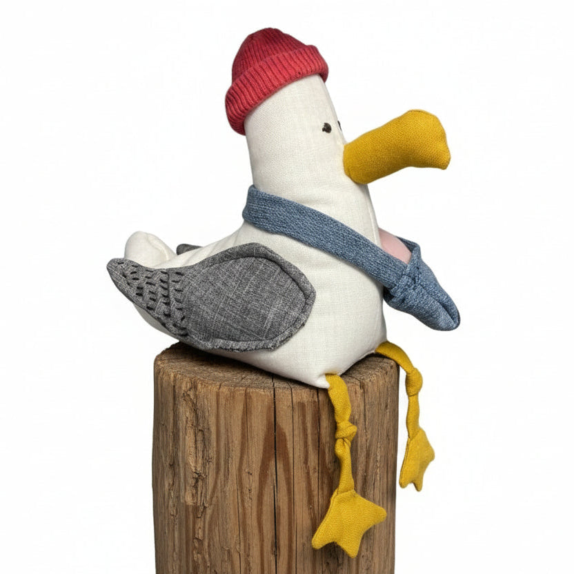 Toy seagull with a red hat and yellow feet on a green container 