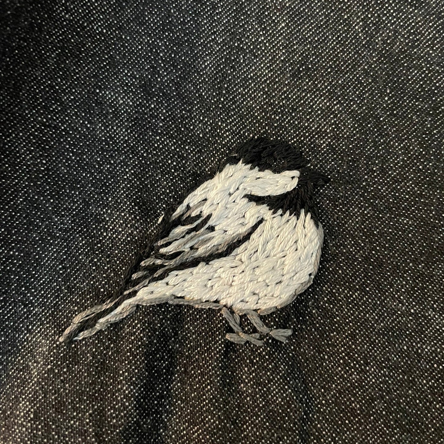 Embroidered chickadee on a dark fabric background