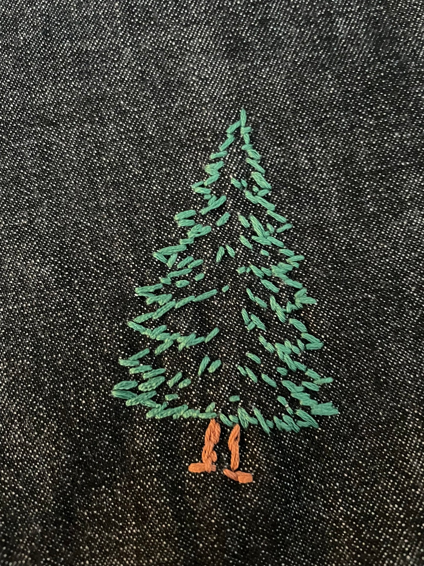 Embroidered green tree design on black fabric