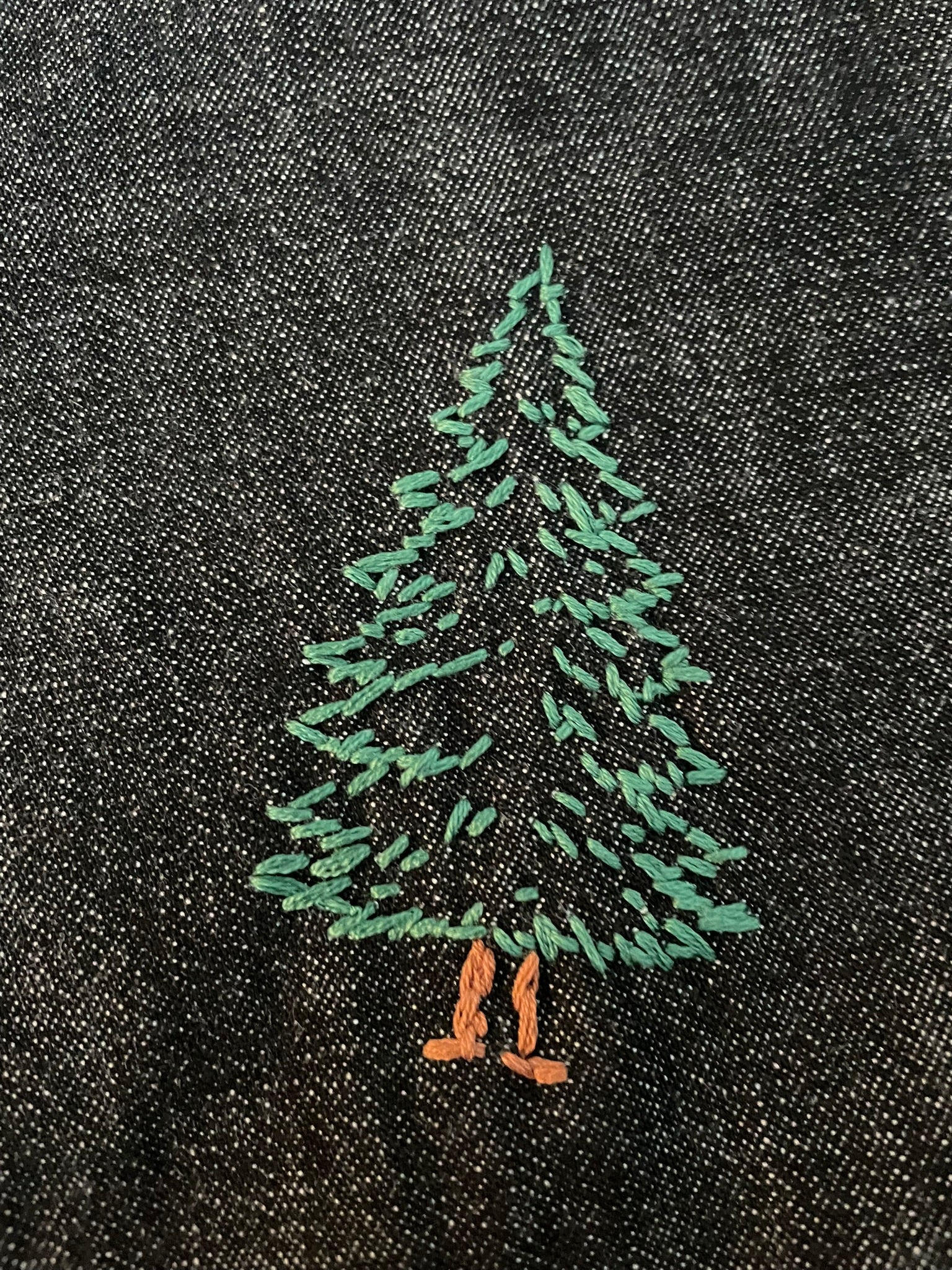 Embroidered green tree design on black fabric