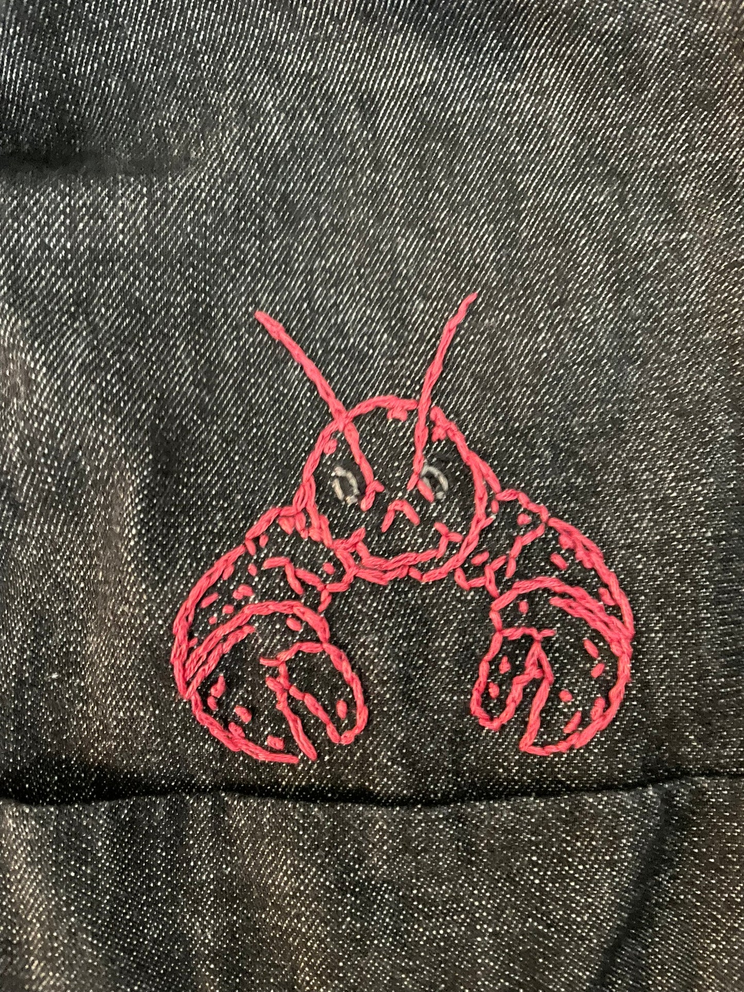 Embroidered red lobster design on dark fabric