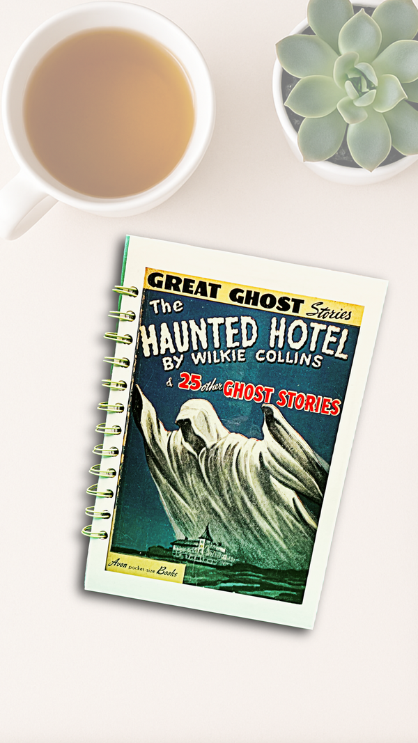 Notebook with 'Haunted Hotel' cover on a white surface with a cup of tea and succulent plant.