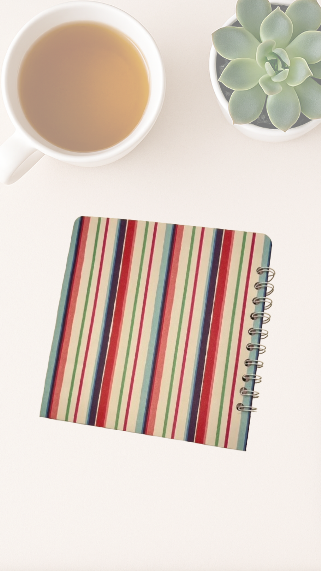 Back cover of colorful striped notebook on a white surface with a cup of tea and succulent plant.