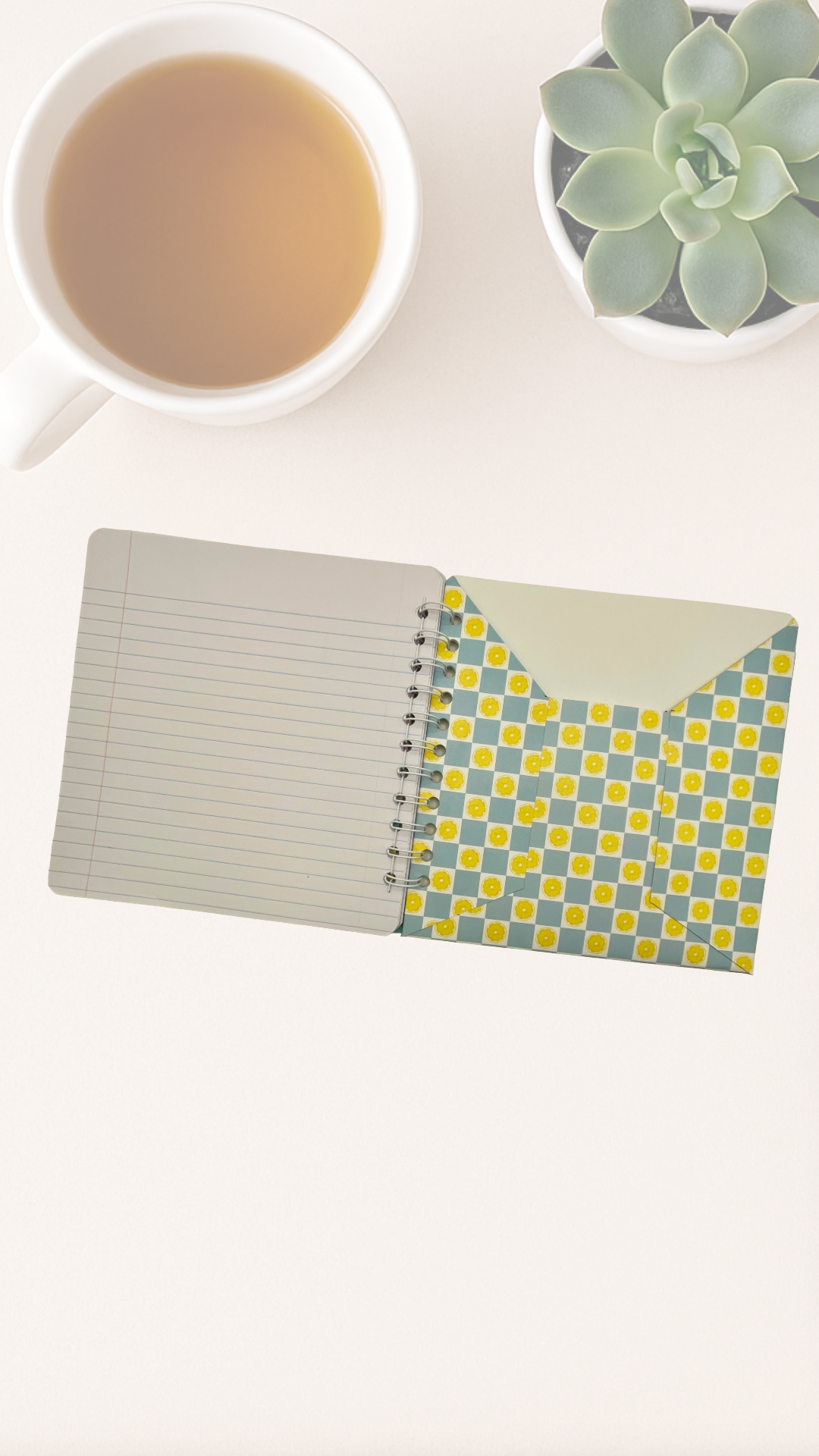 Notebook with a geometric inside cover next to a cup of tea on a white surface