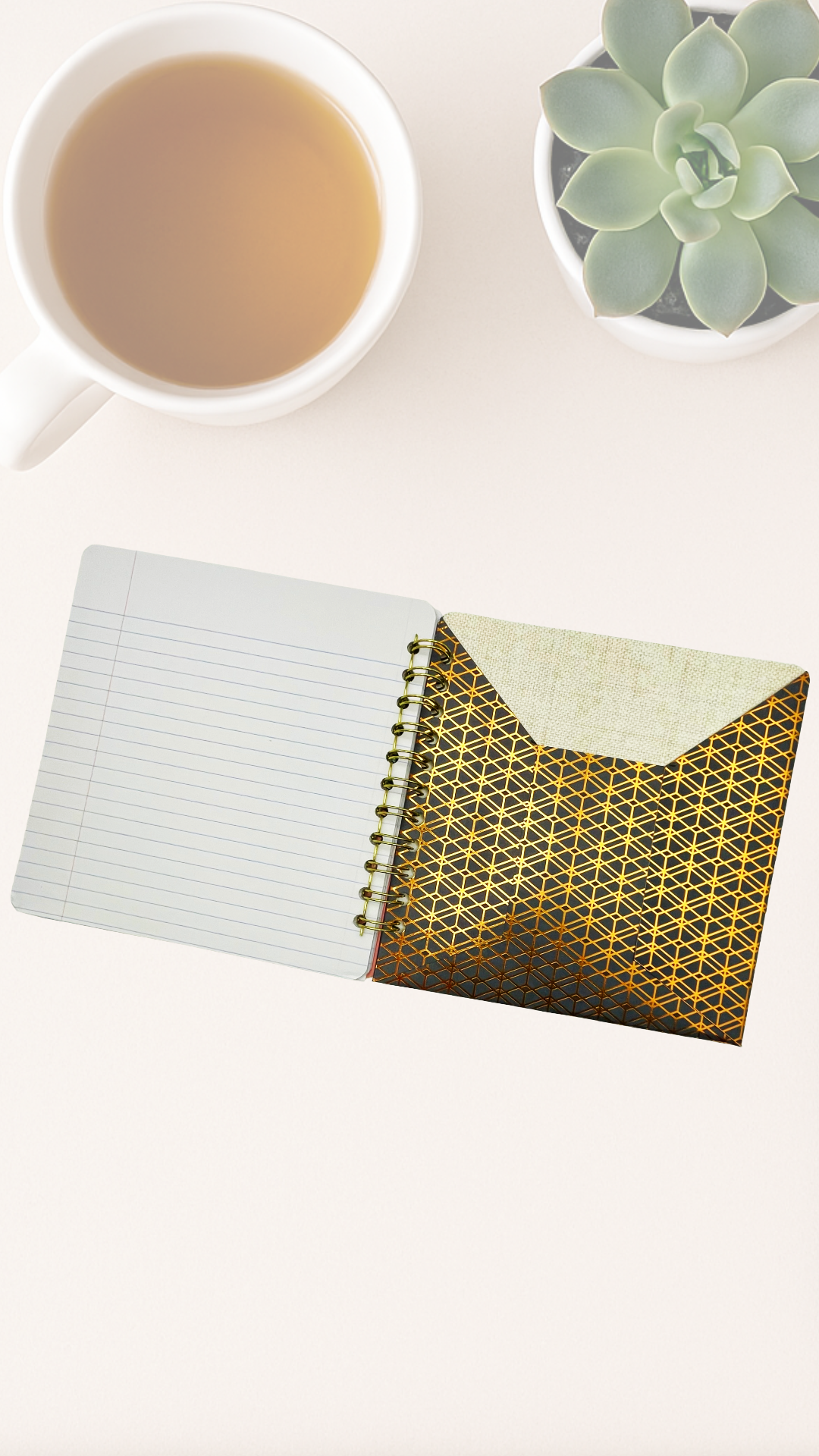 Notebook with geometric cover and cup of tea on a white surface