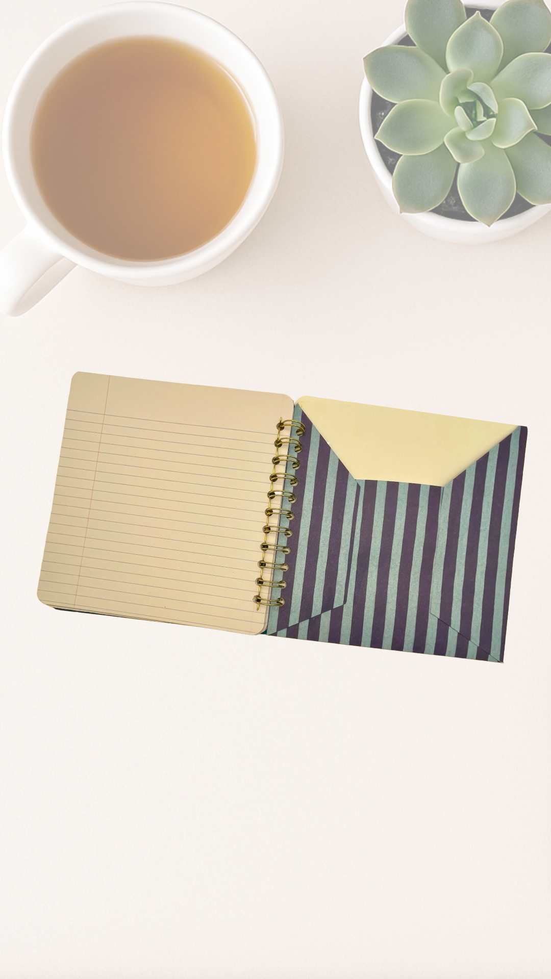 Notebook with inside back striped cover  pocket and plain pages next to a cup of tea on a white surface.