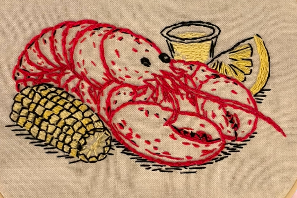 Embroidery hoop with a red lobster design on a textured background