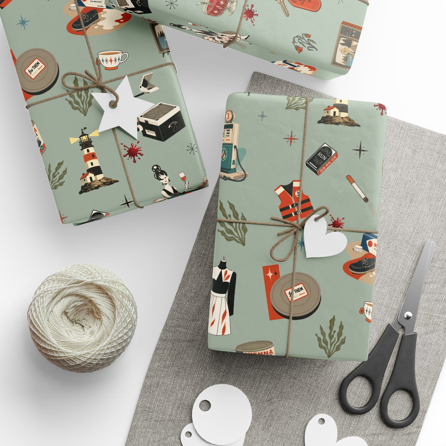 Gift boxes wrapped in patterned paper with a spool of yarn and scissors on a white surface.