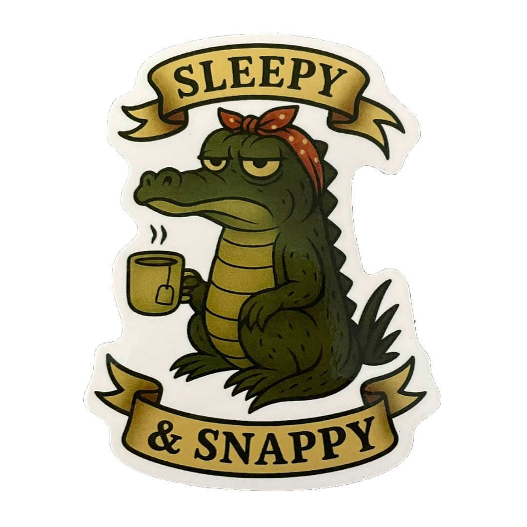 Sticker of a crocodile holding a mug with 'Sleepy & Snappy' text on a white background