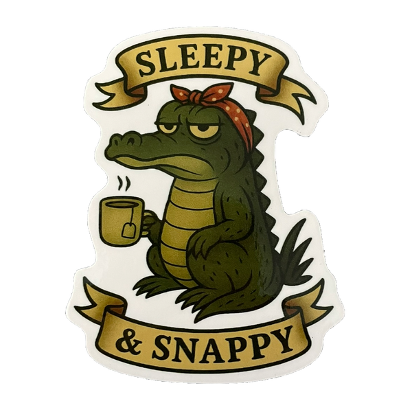 Sticker of a crocodile holding a mug with 'Sleepy & Snappy' text on a white background
